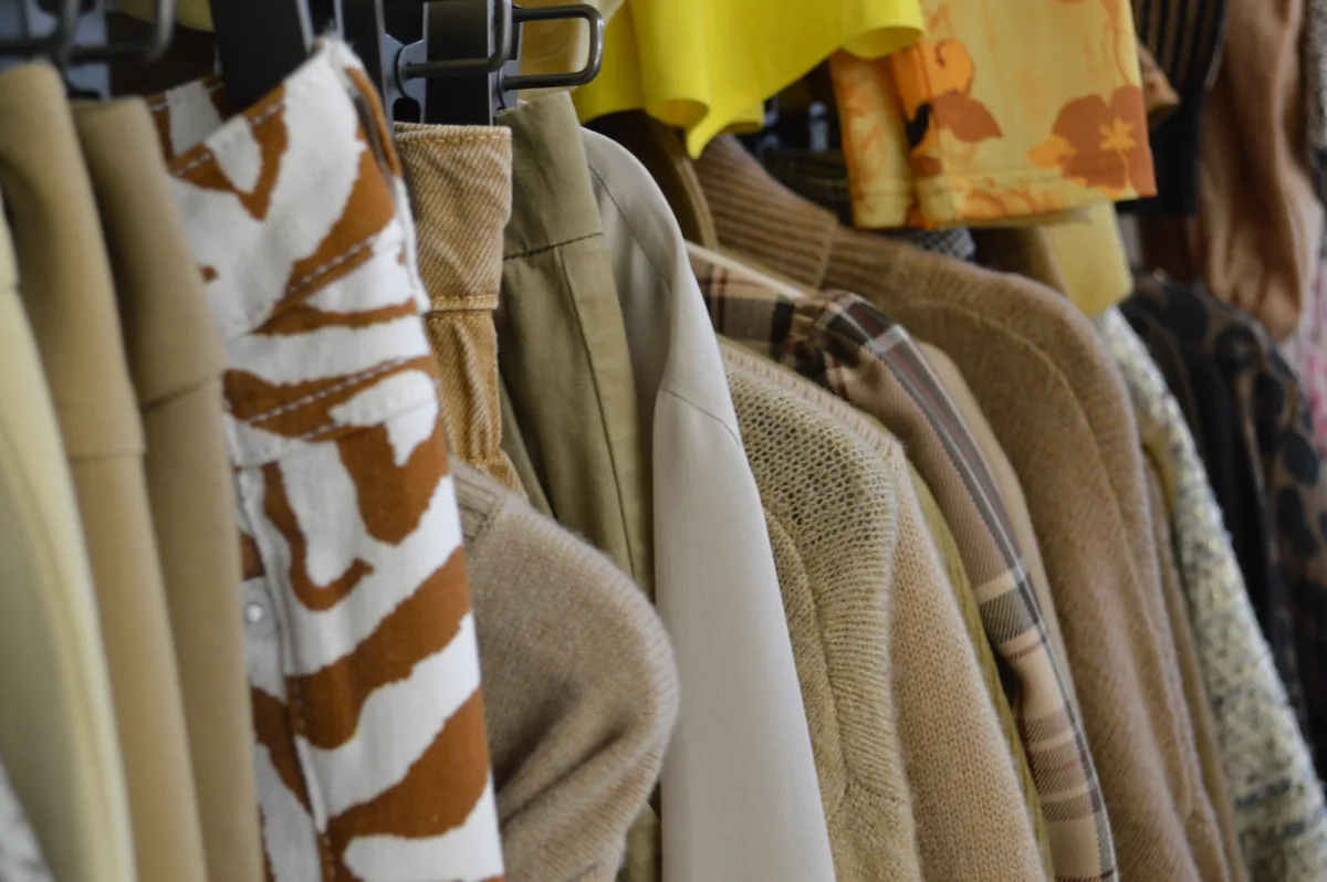 An einer Kleiderstange hängen Kleidung in Brauntöne.